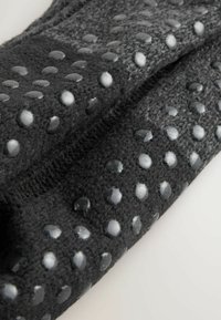 Sort fleece-stof med hævede, blanke cirkulære detaljer, der har en struktureret overflade og et kontinuerligt strikket design.