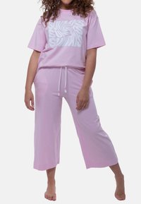 Rosa loungewear-set som består av en rymlig t-shirt med vit virvelgrafik och matchande korta byxor med elastisk midja och dragsko.