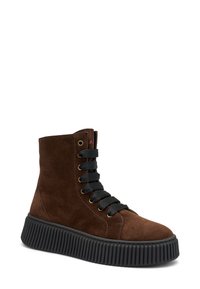 Zapatillas altas de ante marrón con cordones negros, ojales dorados y una suela de goma negra texturizada con un diseño acanalado.