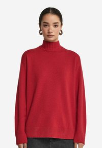 Roter, gerippter Rollkragenpullover mit lässiger Passform, langen �Ärmeln und texturiertem Finish, kombiniert mit einem minimalistischen Design.