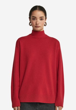 Roter, gerippter Rollkragenpullover mit lässiger Passform, langen Ärmeln und texturiertem Finish, kombiniert mit einem minimalistischen Design.
