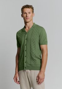 Korte mouw geweven shirt in olijfgroen met een gestructureerd ruitpatroon, knoopsluiting en een geknipte kraag. Gladde katoenmix stof.