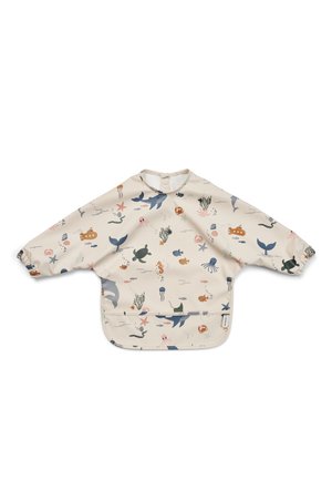 Beige langarmige peuterschort met elastische manchetten en oceaanthema prints met onder andere walvissen, schildpadden, vissen, dolfijnen en zeewier.