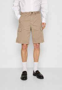 Pantaloni cargo beige con tasche laterali, chiusura a bottone e cintura elastica, realizzati in un tessuto resistente. Design classico a metà coscia.