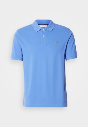 Polo azul de algodón, con cuello clásico, tapeta de dos botones y un logo bordado en el pecho. Mangas cortas.