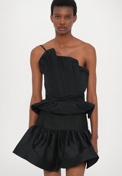 Vestido negro asimétrico con pliegues estructurados en el busto, cintura de peplum y dobladillo con volantes. Fabricado en una tela suave con acabado mate.