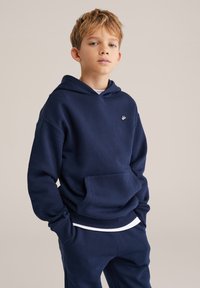 Tumesinine kapuutsiga särk, mis on valmistatud pehmest kangast, millel on känguru tasku, soonikkoes varrukad ja allääre, ning rinnal väike logo.