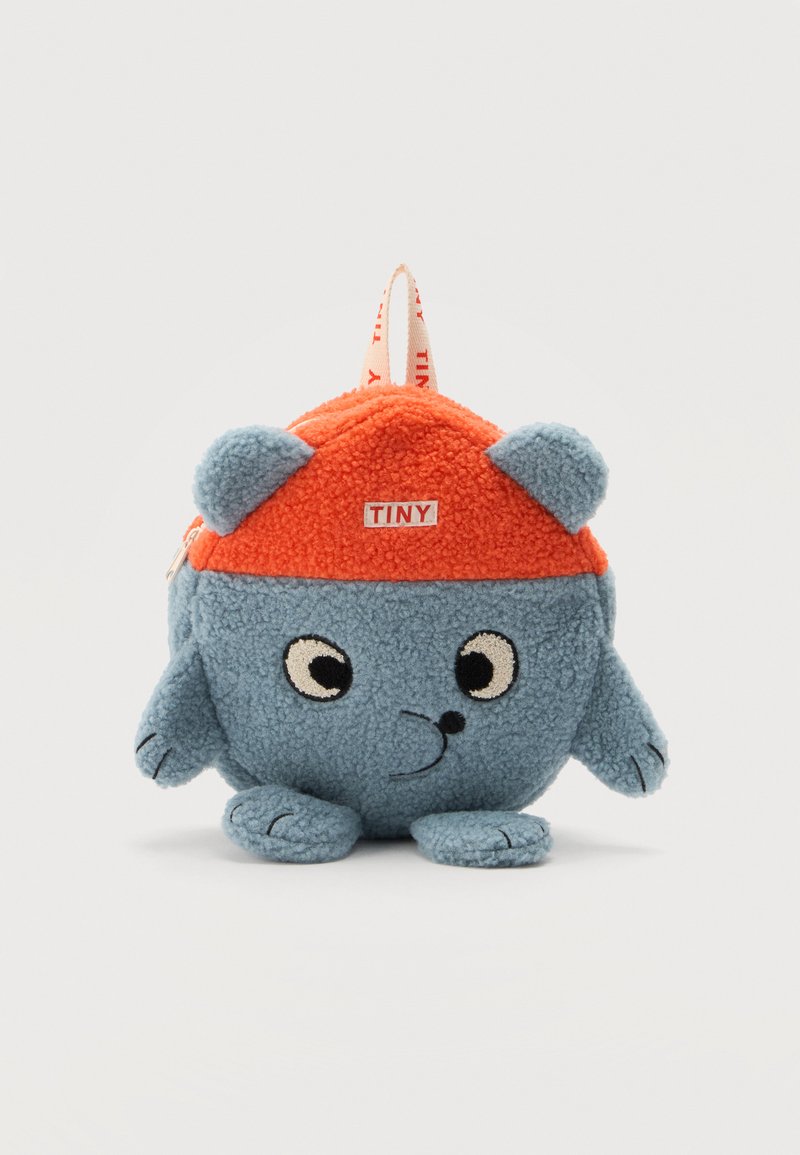 Petit sac à dos rond en peluche bleu avec un dessus orange, visage de dessin animé, oreilles, bras, pieds, et une étiquette "TINY" à l'avant.