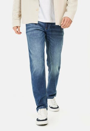Lyseblå denim jeans med lige ben, som har slidte accenter, syede detaljer og er parret med hvide sneakers.