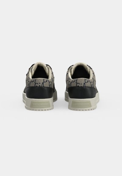 Paire de baskets basses en tissu beige à motifs avec détail noir au talon, vues de dos sur fond blanc.
