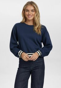 Felpa blu navy con polsini e orlo a coste righe bianche e nere. Presenta un collo tondo e una vestibilità comoda, realizzata in tessuto morbido.