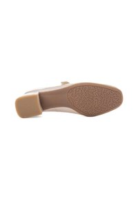 Zapato beige claro con un empeine sintético suave y una suela de goma texturizada, que presenta un tacón bajo y redondeado, así como un detalle de patrón sutil.