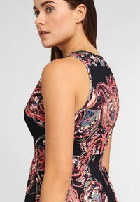 Vestido sin mangas con una tela negra adornada con un colorido patrón floral en espiral, cintura elástica y escote redondo.