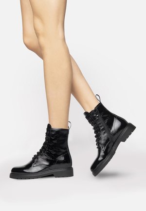 Black patent leather ankle boots with a glossy finish, round toe, lace-up front, and textured side panels. Features a low block heel.
