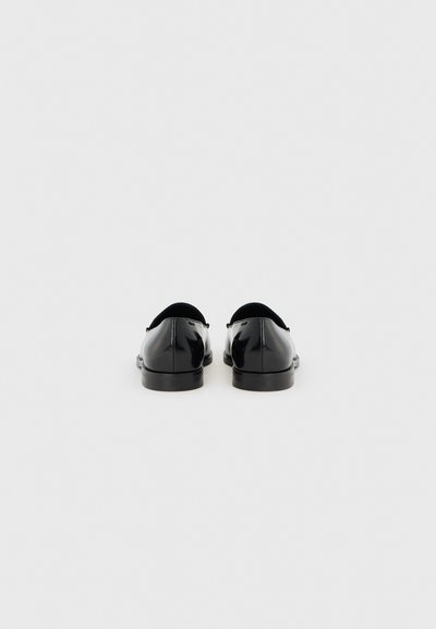 Μαύρα δερμάτινα παπούτσια με γυαλιστερή υφή, στρογγυλή μύτη και επίπεδες σόλες· διαθέτουν λεπτομέρεια ραφής κατά μήκος των άκρων.