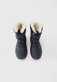 Ein Paar schwarze und marineblaue Winterstiefel mit pinken und weißen Sternmustern, doppelten Klettverschlüssen und einem cremefarbenen Fleece-Innenfutter.