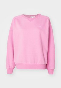 Roze sweatshirt gemaakt van zachte, textuurstof. Beschikt over een V-halslijn, verlaagde schouders en ribgebreide manchetten en zoom. Subtiel logo-detail op de borst.