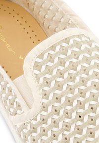 Beige instapper met een geweven bovenkant met een geometrisch patroon, gladde stofaccenten en een gevoerde inlegzool met perforaties.