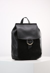 Černý kožený a semišový batoh s magnetickým uzávěrem, zlatými kovovými detaily a jedním horním uchem. Zaoblené dno a plochý zadní panel.