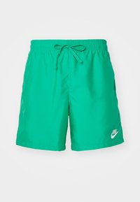 Zelené plavecké šortky Nike vyrobené z lehkého materiálu. Elastický pas se stahovací šňůrkou a malé bílé logo v dolním pravém rohu.
