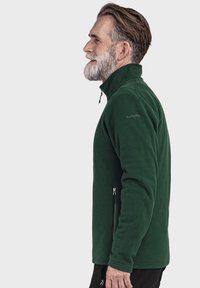 Grüne Fleecejacke mit hohem Kragen, seitlichem Reißverschluss-Taschen und Logodetail an der Schulter. Hat eine weiche, strukturierte Oberfläche.