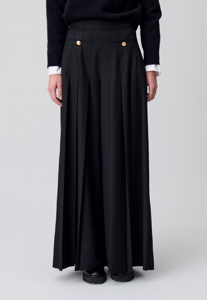 Pantaloni a palazzo neri plissettati con dettagli in bottone dorato, vita alta, design su misura e texture liscia. Si apre dalla caviglia.