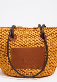 Yellow woven handbag with dark brown round handles and a rectangular brown leather label embossed with "BIMBA Y LOLA" on front.