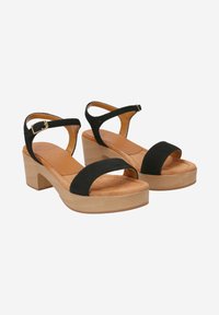 Black suede platform sandals with adjustable ankle strap, wooden block heel, and exposed toe design. Soft, cushioned insole.