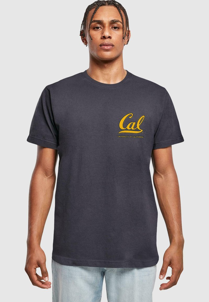 Tricou din bumbac bleumarin, cu mâneci scurte și decolteu rotund; are logo-ul galben "Cal" și textul "Universitatea din California" pe piept.