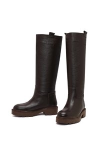 Bruine leren laarzen tot boven de knie met een gestructureerde afwerking, dikke plateauzolen en trekbandjes bovenaan voor gemakkelijk aan- en uittrekken.