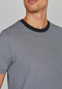 Marineblaues und weiß gestreiftes T-Shirt mit Rundhalsausschnitt und kurzen Ärmeln, ausgestattet mit einem kontrastierenden schwarzen Kragen. Weicher, strukturiertes Material.