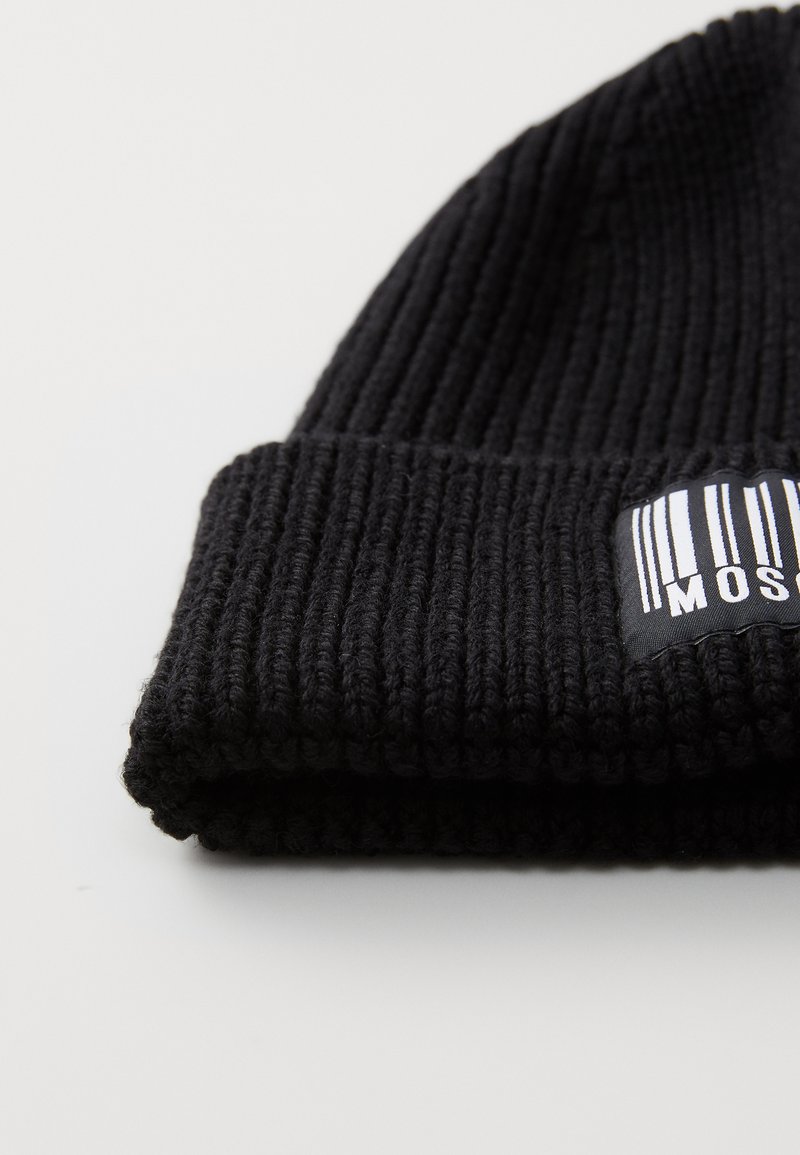 Schwarze gestrickte Mütze mit geripptem Muster und umgekrempeltem Bund. Verfügt über ein rechteckiges Logopatch mit weißen vertikalen Streifen.