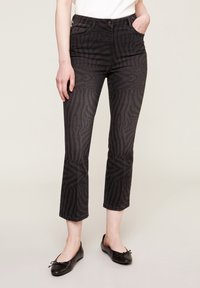 Svarta jeans med ett subtilt zebramönster, med en figursydd midja, raka ben och avskuren nederkant. Bärs med svarta ballerinaskor.