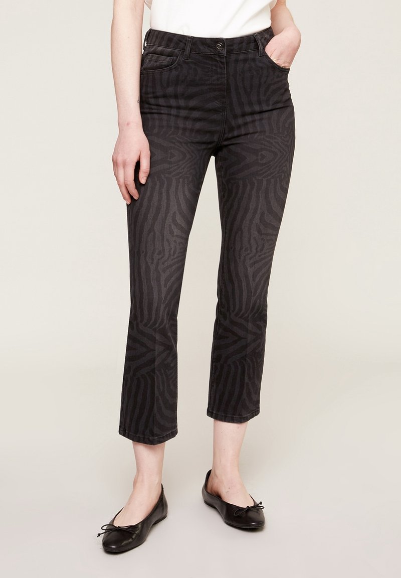 Svarta jeans med ett subtilt zebramönster, med en figursydd midja, raka ben och avskuren nederkant. Bärs med svarta ballerinaskor.