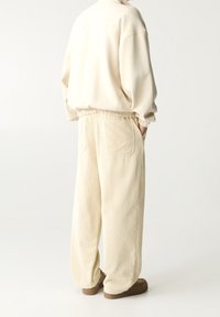 Beige corduroy broek met een ontspannen pasvorm, voorzien van een brede tailleband, zijzakken en een zachte textuur, gecombineerd met een bijpassende trui.