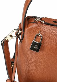 Bruine leren handtas met een gestructureerd oppervlak, voorzien van een ritssluiting en een metalen accent in de vorm van een slot. Inclusief een afneembare schouderband.