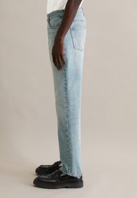 Jeans in denim azzurro chiaro, design a gamba dritta, con classica configurazione a cinque tasche. Indossati con scarpe in pelle nera. Tessuto liscio, sbiadito al minimo.