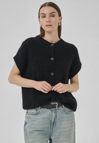 Black short-sleeve cardigan with textured material, five buttons, and a round neckline, paired with light blue high-waisted jeans and a black belt.
