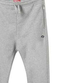 Pantaloni da jogging grigi realizzati in un tessuto morbido, con una vita elasticizzata, tasca laterale con zip e un piccolo logo nero sulla coscia sinistra.