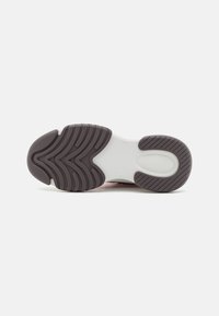 Suela de zapato con un diseño texturizado y ranuras onduladas, predominantemente de goma marrón oscuro con una entresuela blanca.
