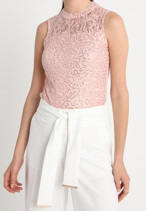 Różowy top bez rękawów z koronką, zestawiony z białymi, wysokim stanem spodniami, wyposażonymi w szeroki pas materiałowy zawiązany w talii.