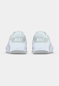 Λευκά παπούτσια Nike με επάνω μέρος από δίχτυ, διαθέτοντας αντίθετη ανοιχτό γκρι περιοχή στη φτέρνα και εμφανές λογότυπο Nike στο πίσω μέρος.