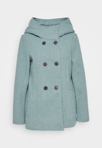 Dubbelzijdige jas van geborsteld teal stof met grote zwarte knopen, een capuchon en zijzakken. Gelaagdheid met subtiel patroon.