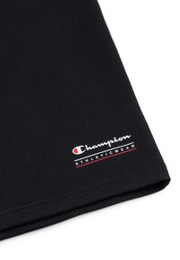 Zwarte katoenen stof met een gevouwen rand. Het "Champion"-logo is in het wit geborduurd met een rode accent, gelabeld "ATHLETICWEAR."