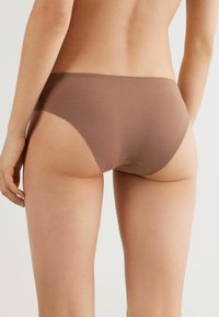 Braune nahtlose Unterwäsche mit niedrigem Schnitt, gefertigt aus glattem, dehnbarem Material und sauberen Kanten, entworfen für Komfort und minimale Sichtbarkeit.