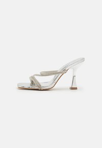 Silver heeled sandals with crisscross straps. Made of glossy material with a textured surface, featuring a squared toe and a geometric heel.