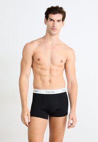 Zwarte boxershorts met een witte Calvin Klein-logo op de elastische tailleband, voorzien van een strakke pasvorm en een gladde katoenstof.