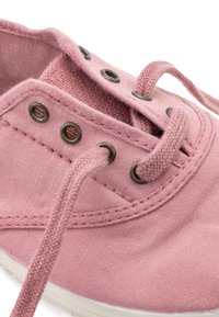 Zapatillas de lona rosa con ojales de metal redondos y cordones estampados. Presentan una suela de goma blanca y una textura suave en toda su superficie.
