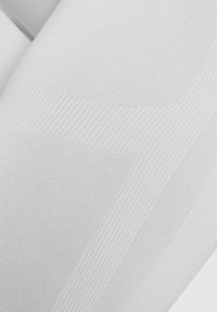 Weiße, strukturierte Strumpfhosen mit geripptem Design. Glatter, eng gewebter Stoff mit leichtem Glanz, der eine enge Passform und Dehnung betont.
