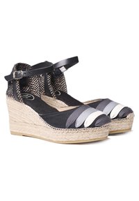 Cuñas de espadrille de tela negra con suela de yute trenzado, tirante en el tobillo y bandas apiladas en gris y blanco en la zona de los dedos. Detalles texturizados presentes.